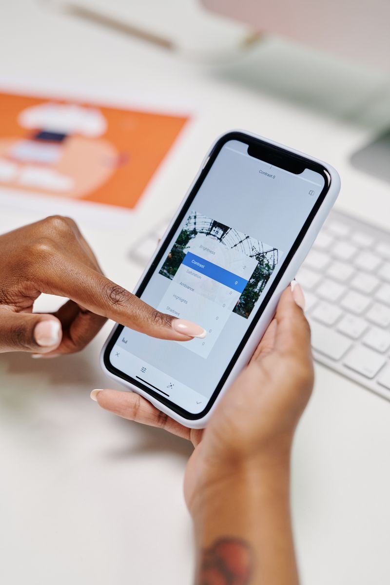 A group of friends sitting around a table with phones showing a shared expense tracking app.
